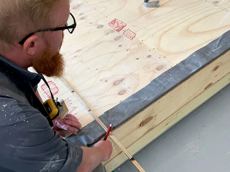 Medarbejder i produktionen tager mål til montage af badekabiner