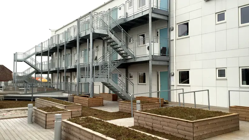 Plantekasser bygget i træ, sammen med en stor fælles træterrasse i baggården til Taastrup Torv. Trappegangen og svalegangene som leder til indgangene til lejlighederne.